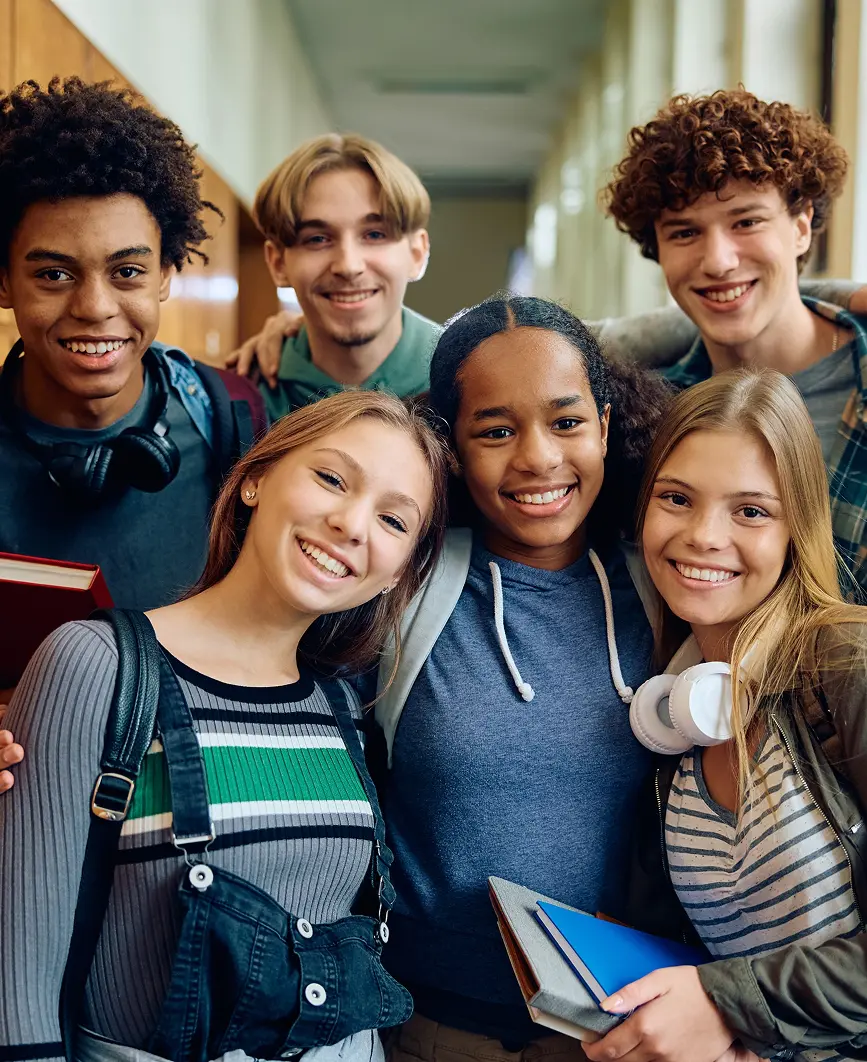 Group of smiling students in a hallway.