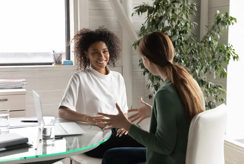 Two women having a conversation in office.