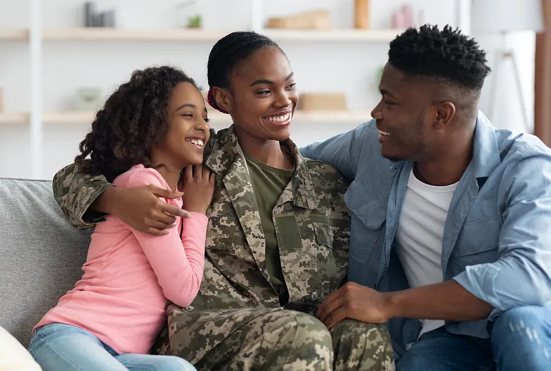 Soldier with family on a couch, smiling.