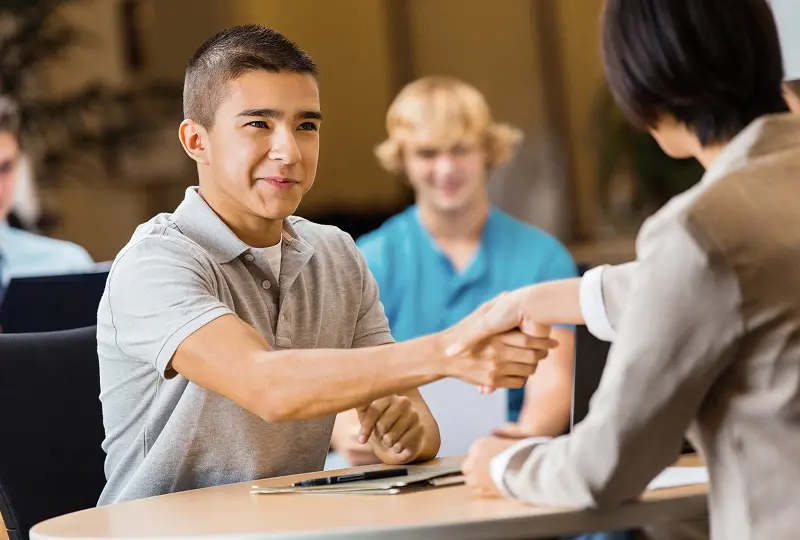 Two people shaking hands at a table.